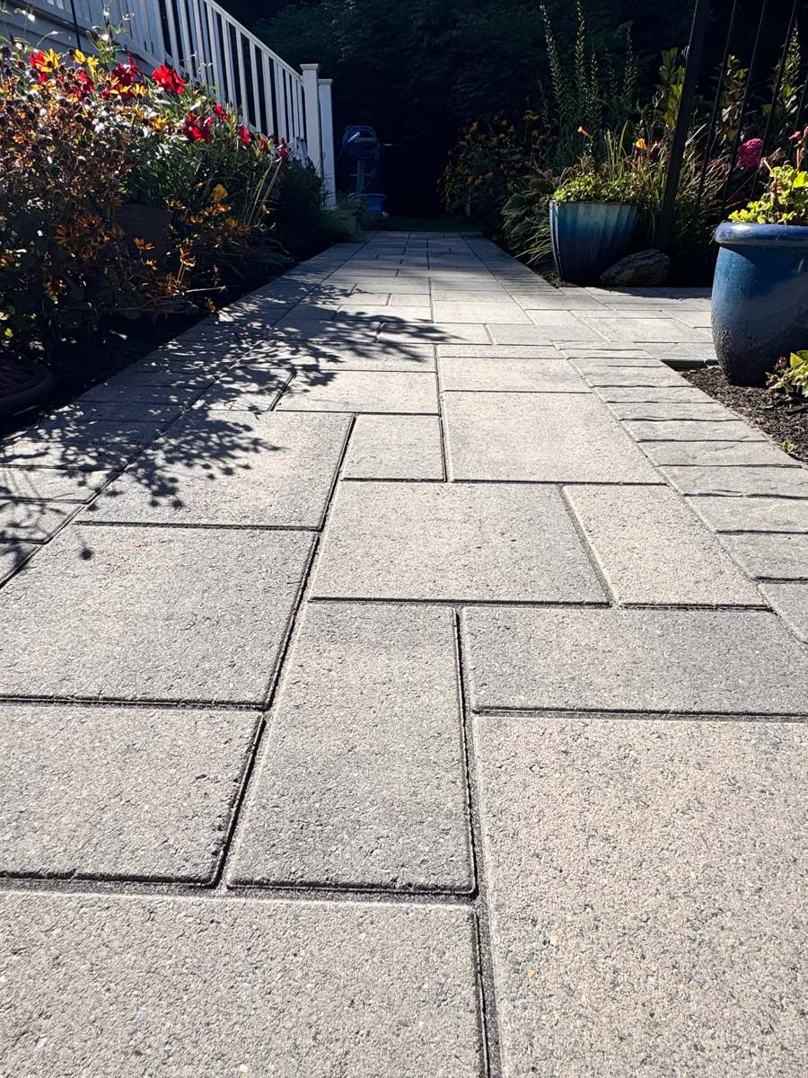 Paver garden walkway beside a white railing, cleaned and sealed